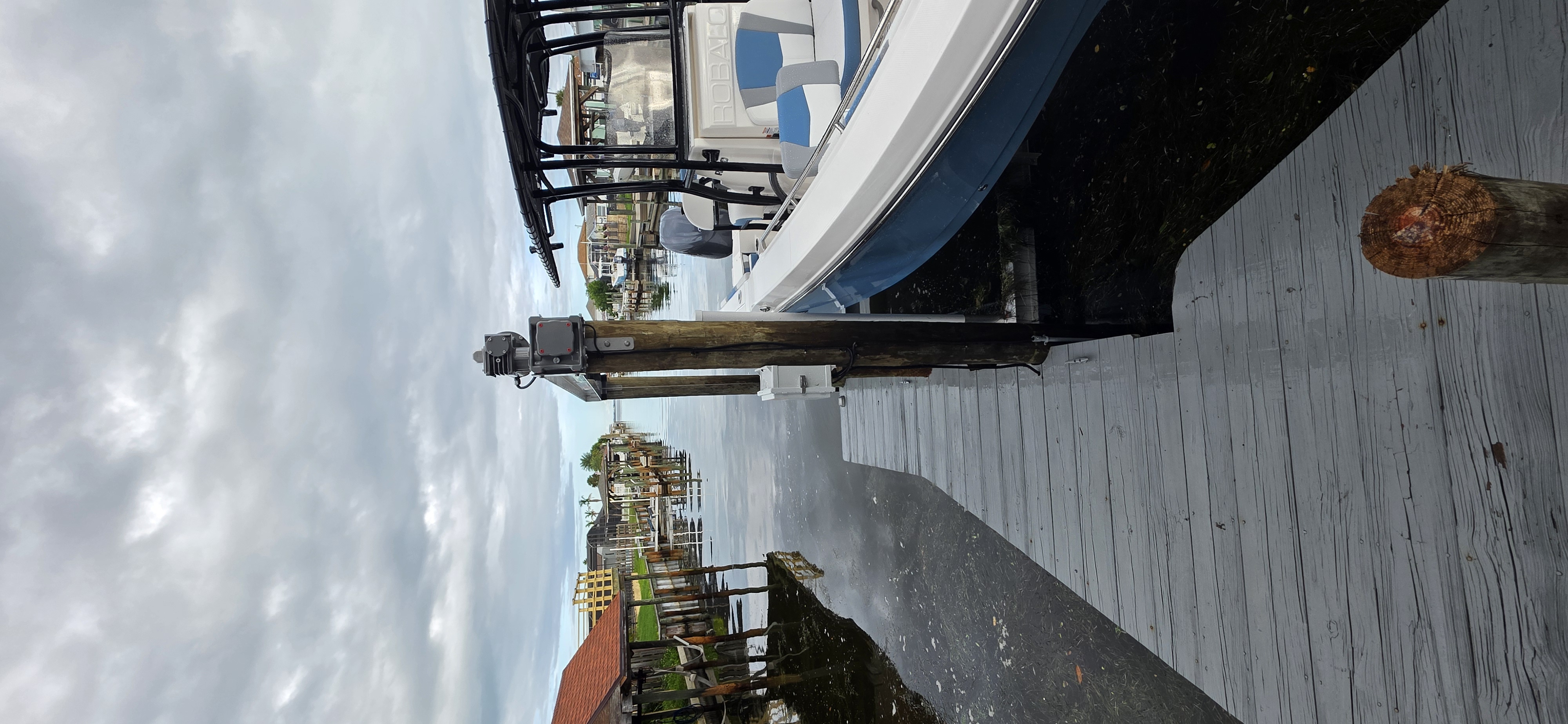 Blue center-console boat raised on a Hurricane Boat Lift beside a canal dock